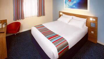 A hotel room with a large bed, a red chair, a desk with a telephone, and a painting on the wall.