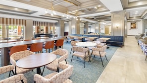 A spacious dining area with multiple tables and chairs, a bar, and a seating area with couches.