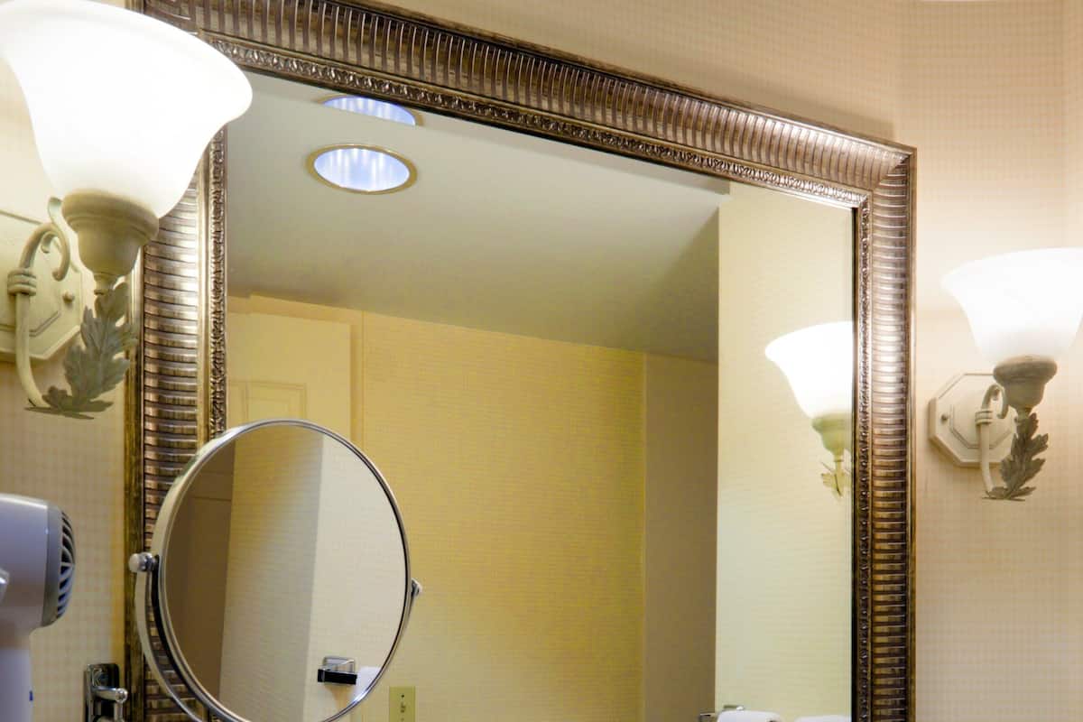 A bathroom with a large mirror, a sink, and a towel rack.