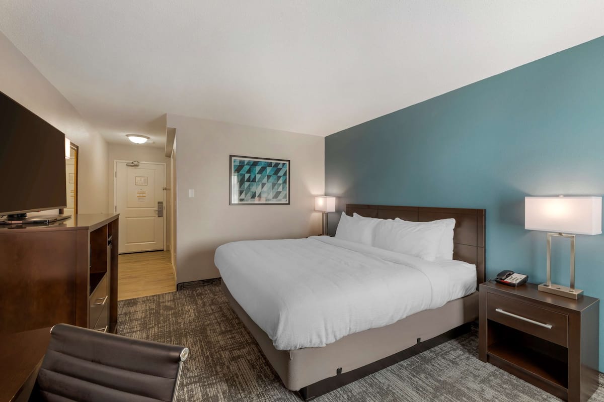 Een hotelkamer met een bed, nachtkastjes, een bureau en een stoel.