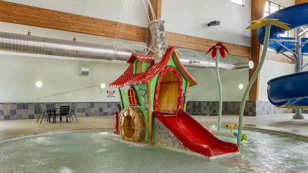 Een overdekt waterpretpark met een glijbaan, een speelhuis en een zwembad.