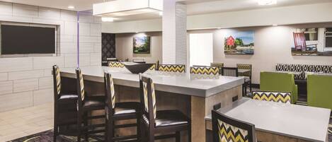 A modern hotel lobby with a bar area, seating with patterned cushions, and artwork on the walls.