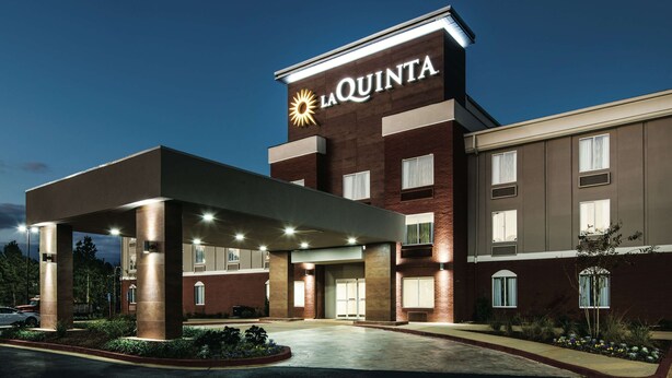 A La Quinta hotel with a modern design, featuring a prominent sign, a covered entrance, and a landscaped area in front. - La Quinta Inn & Suites by Wyndham Milledgeville (Milledgeville)