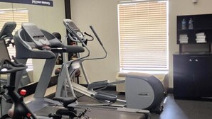 A gym with stationary bikes, treadmills, and a mirrored wall.