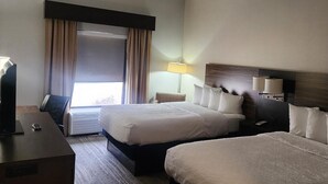 A hotel room with two beds, a desk, a chair, a lamp, and a large window with curtains.