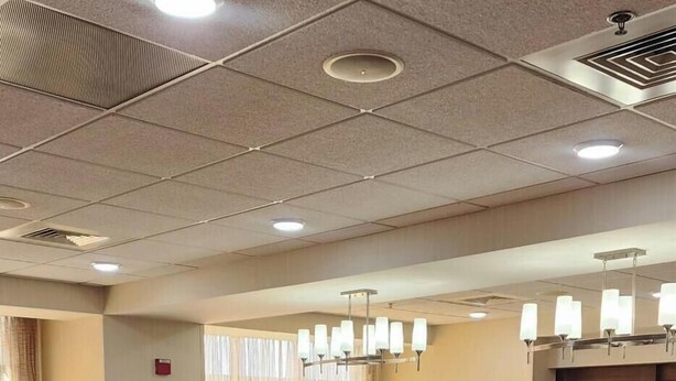 A hotel lobby with a seating area, a reception desk, and a large window with curtains.
