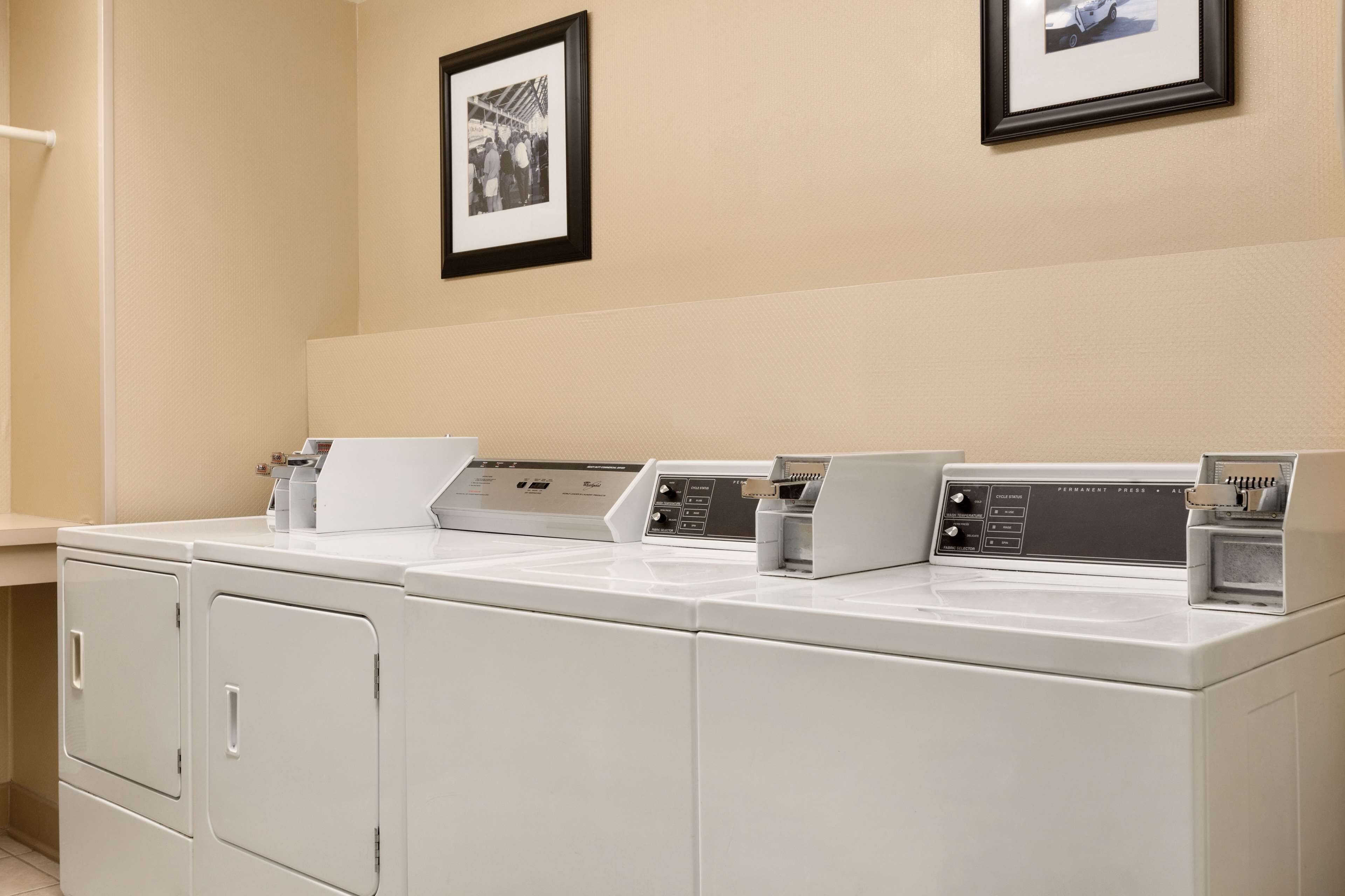 A laundry area with three washing machines and two dryers.