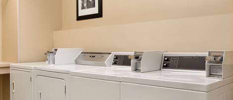 A laundry area with three washing machines and two dryers.