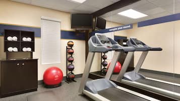 A gym with treadmills, exercise balls, and a cabinet.