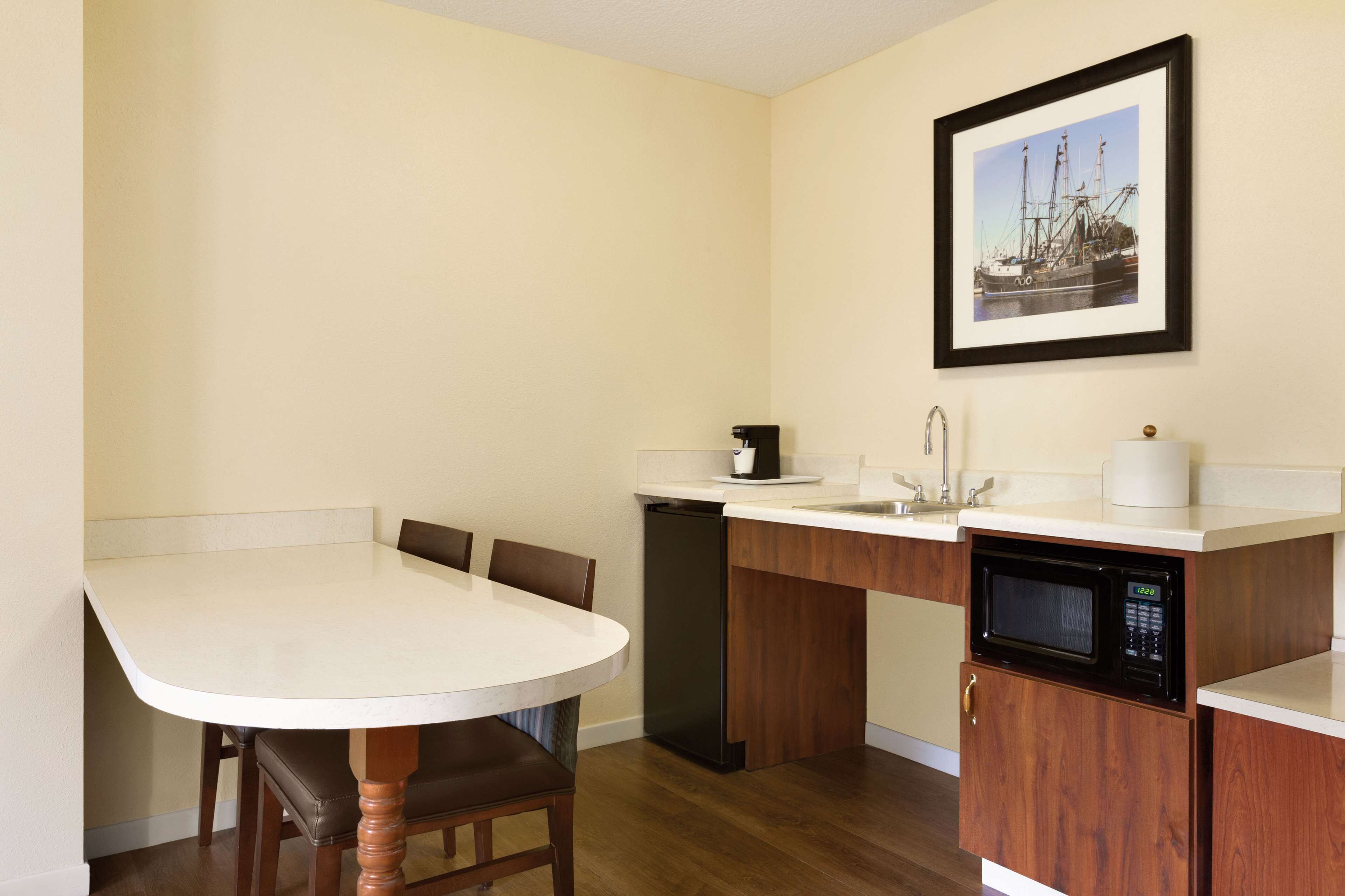 A compact kitchen with a dining table, chairs, a dishwasher, a microwave, and a sink.