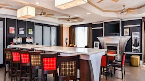 Een moderne keuken met een centraal eiland, barkrukken, plafondventilatoren en een open haard.