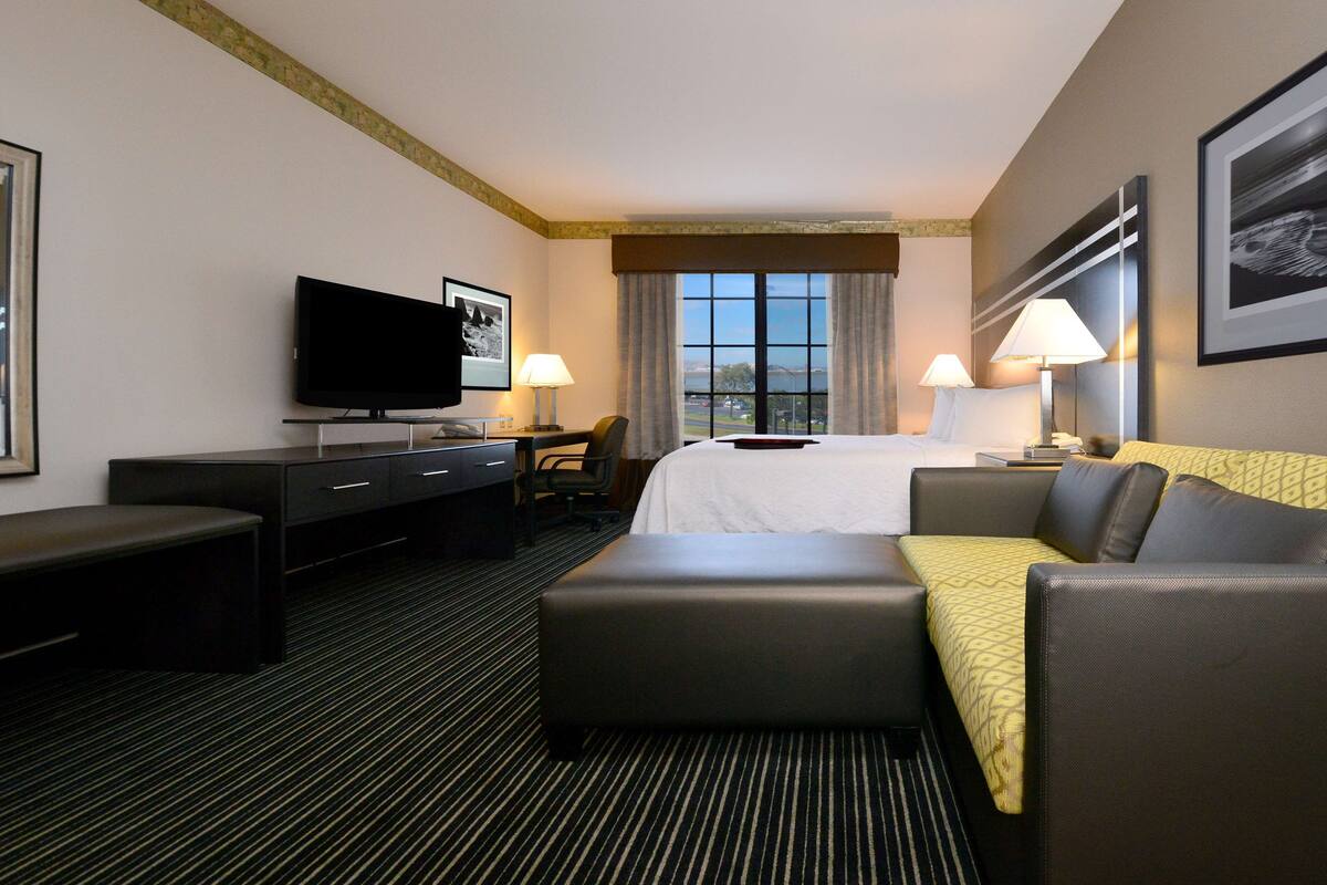 Une chambre d’hôtel comprenant un lit, une télévision, un bureau et un coin salon.