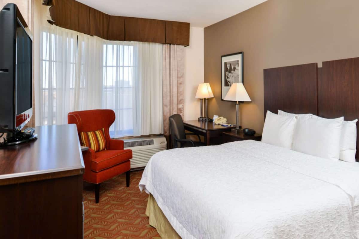 Une chambre d’hôtel avec un grand lit, un bureau équipé d’un ordinateur, une chaise et un téléviseur.