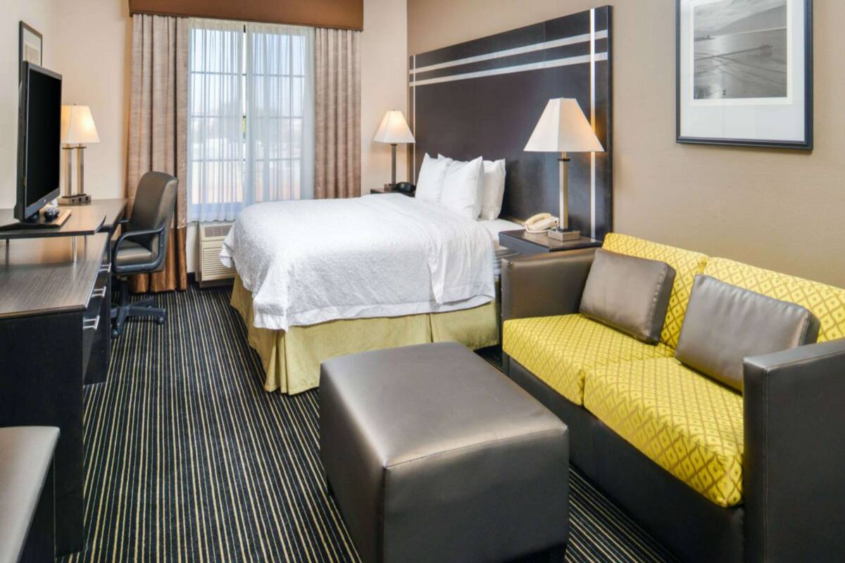 Une chambre d’hôtel comprenant un lit, un canapé, un bureau, une chaise et un téléviseur.