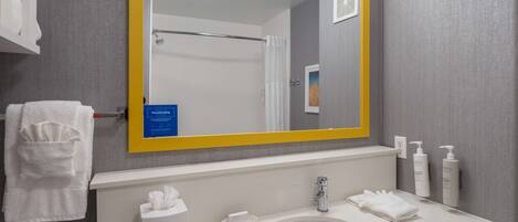 A bathroom with a white sink, a mirror with a yellow frame, and toiletries on the wall.