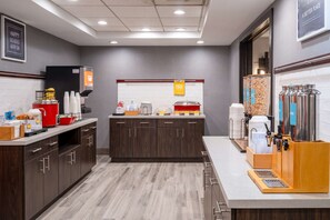 A modern kitchen with a coffee station, a sign for eggs, and a breakfast bar.