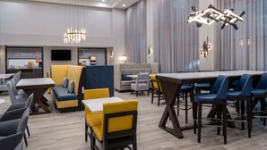 Eine moderne Hotelhalle mit Sitzgeboten, einer Rezeption und einem großen Esstisch.