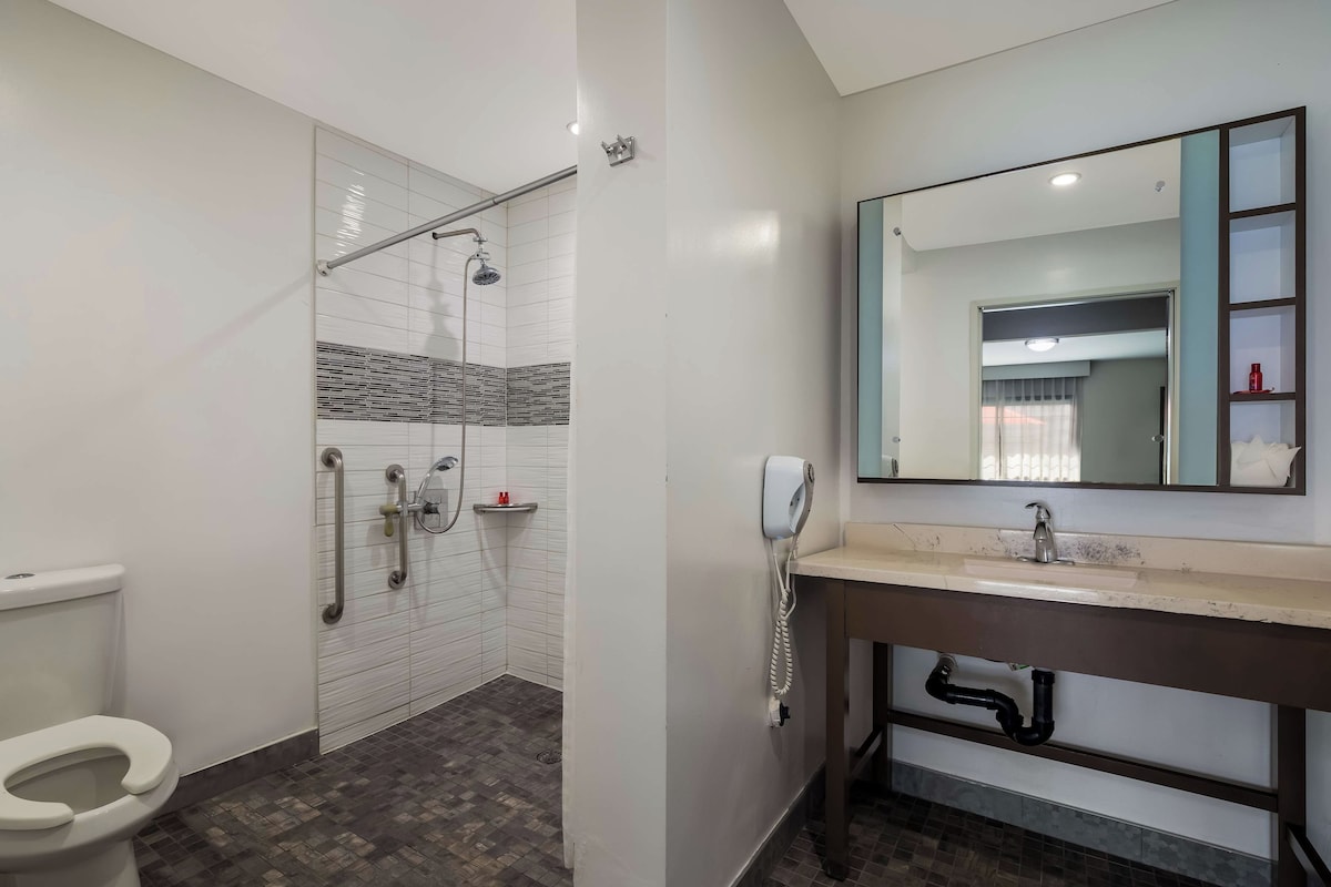 A bathroom with a shower, toilet, sink, and a mirror.