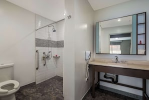 A bathroom with a shower, toilet, sink, and a mirror. - Sunset West Hotel, Surestay Collection By Bw (Los Angeles)