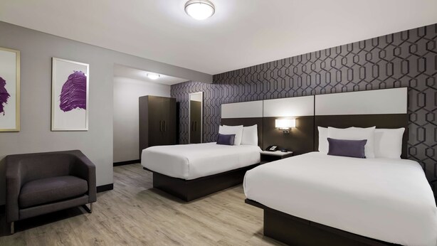 A hotel room with two beds, a desk, a chair, and a large mirror. - Sunset West Hotel, Surestay Collection By Bw (Los Angeles)