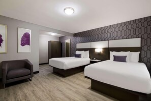 Ein Hotelzimmer mit zwei Betten, einem Sofa, einem Spiegel und Kunstwerken an der Wand.