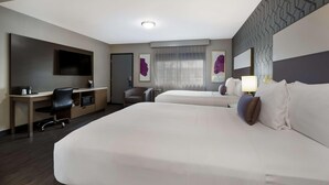 A hotel room with two beds, a desk with a chair, a TV, and artwork on the walls. - Sunset West Hotel, Surestay Collection By Bw (Los Angeles)