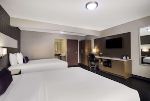 A hotel room with two beds, a desk with a chair, a television, and a microwave. - Sunset West Hotel, Surestay Collection By Bw (Los Angeles)