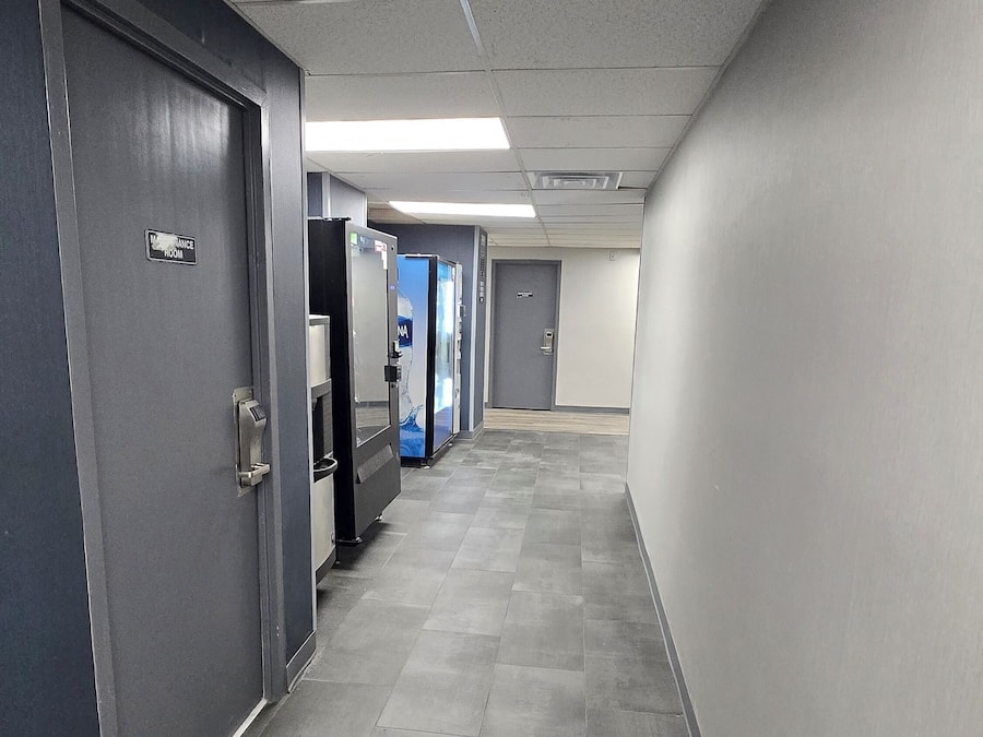 A corridor with doors on the left, a vending machine, and a blue door at the end.