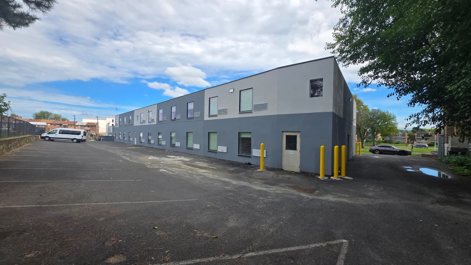 A building with a row of windows and a parking lot in front.