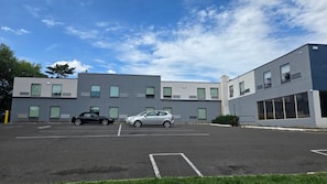A parking lot with two cars, a building with multiple windows and a flat roof, and a clear sky. - Roosevelt Inn (Philadelphia)