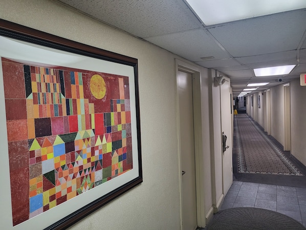 A hallway with a colorful abstract painting on the wall, doors leading to rooms, and a patterned carpet. - Roosevelt Inn (Philadelphia)