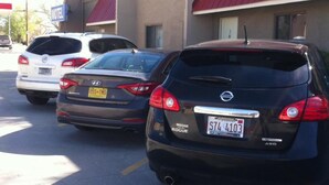 A row of parked cars in front of a motel with a red awning. - National 9 Inn Sand Canyon (Cortez)