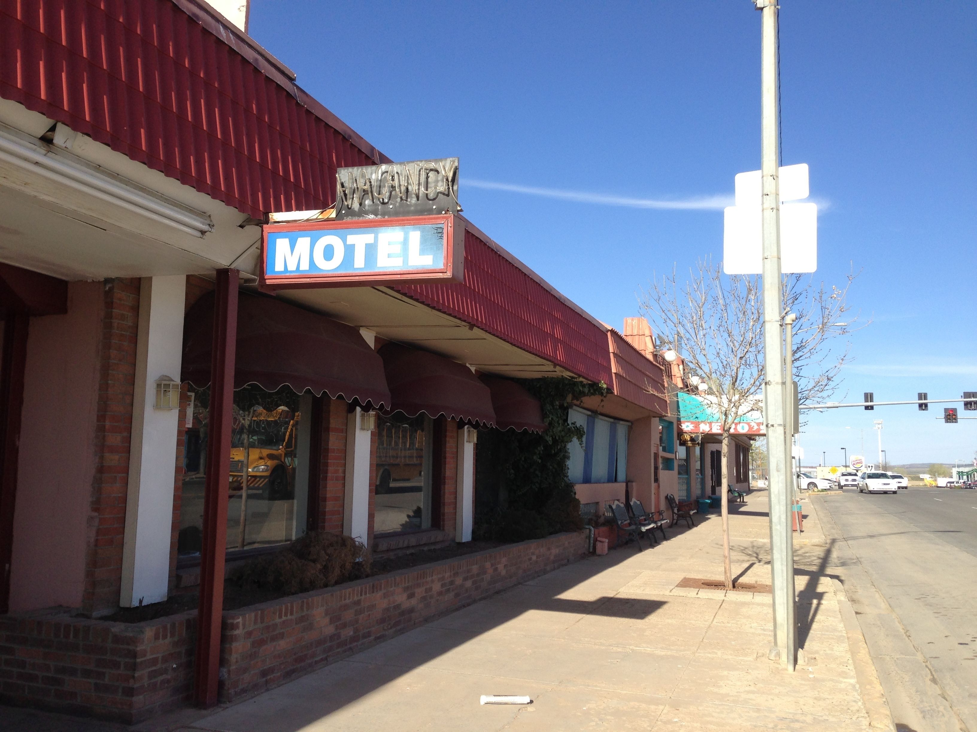 A motel with a red awning and a neon sign.