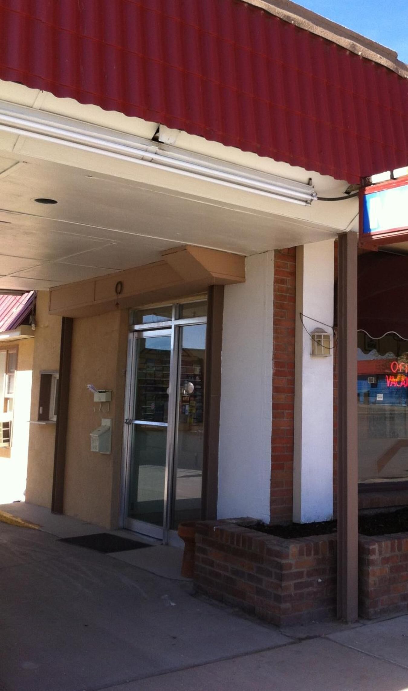 A building with a red roof, a glass door entrance, and a brick base.