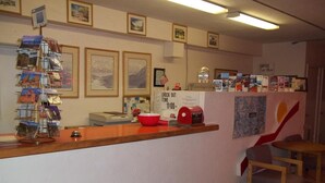 A reception area with a wooden counter, a red bowl, a clock, and framed pictures on the wall. - National 9 Inn Sand Canyon (Cortez)