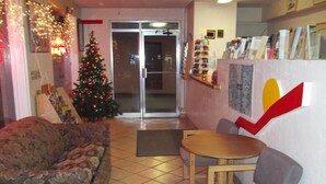 A cozy lobby with a Christmas tree, a sofa, and a small table. - National 9 Inn Sand Canyon (Cortez)