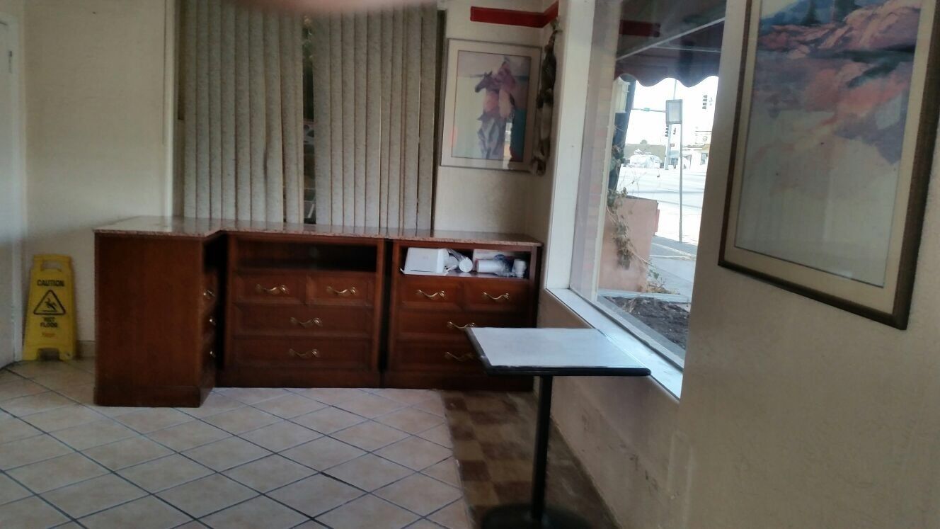 Una habitación con un armario de madera, una mesita y una ventana con vista a la calle.