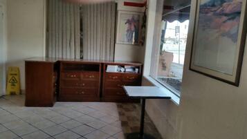 Una habitación con un armario de madera, una mesita y una ventana con vista a la calle.