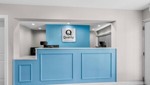 Una recepción con una decoración azul y blanca, el logotipo de 'Quality by Choice Hotels' y un diseño moderno.