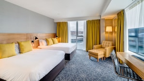 A hotel room with two beds, a desk, a chair, and a large window with curtains. - Apex City Quay Hotel & Spa (Dundee)