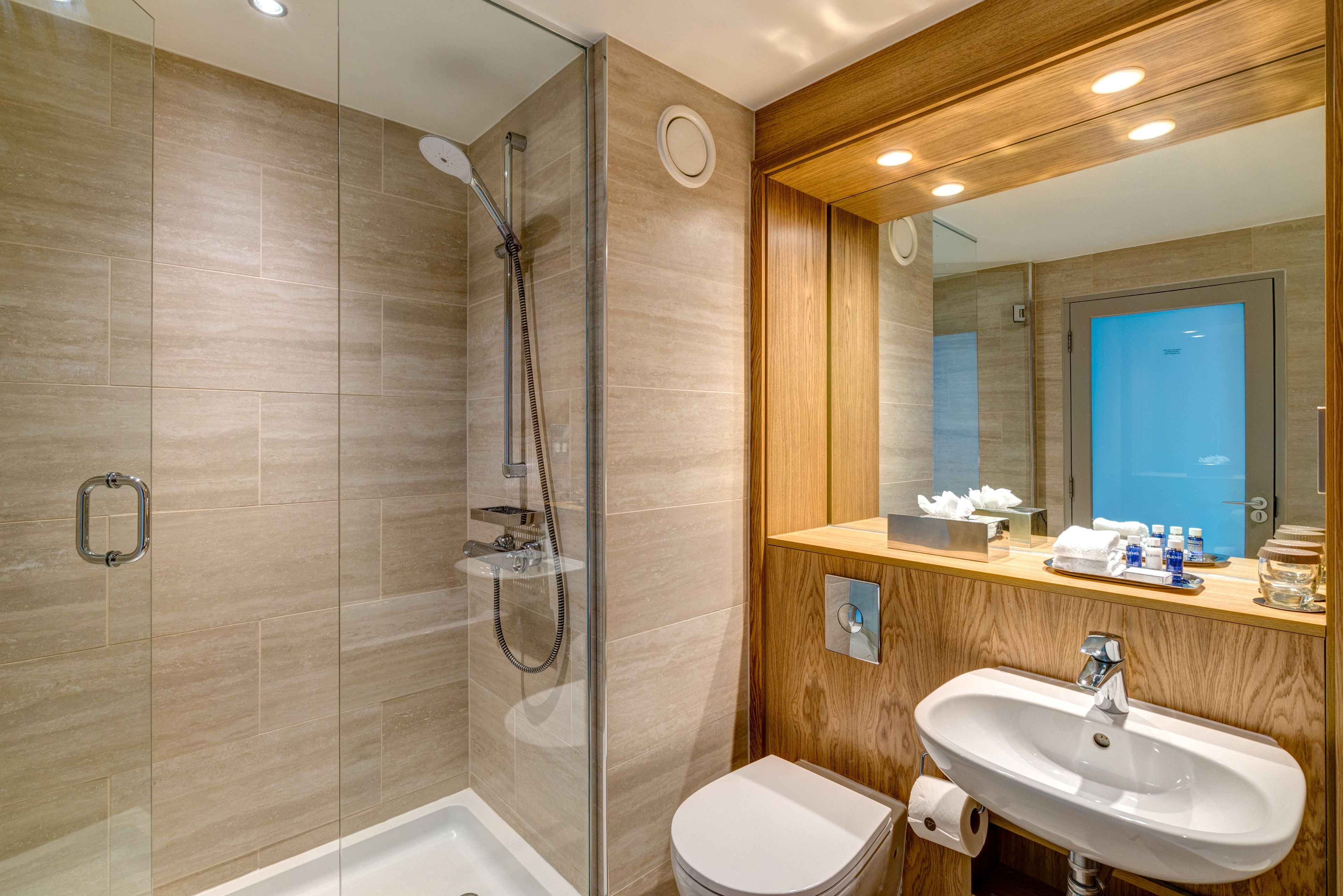 A modern bathroom with a glass-enclosed shower, a wooden vanity with a sink, and a toilet.