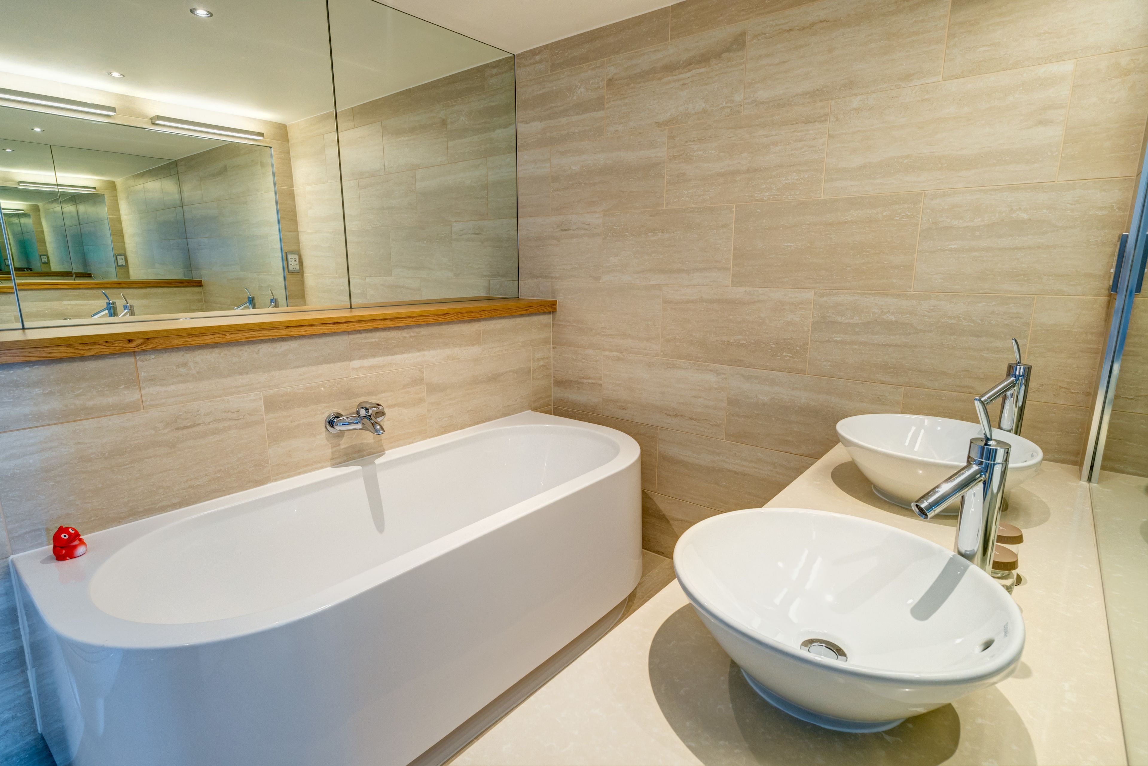 A modern bathroom with a freestanding bathtub, a round sink, and a large mirror.