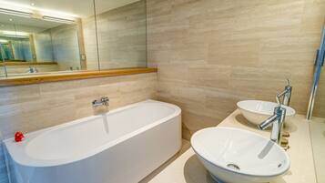 A modern bathroom with a freestanding bathtub, a round sink, and a large mirror.