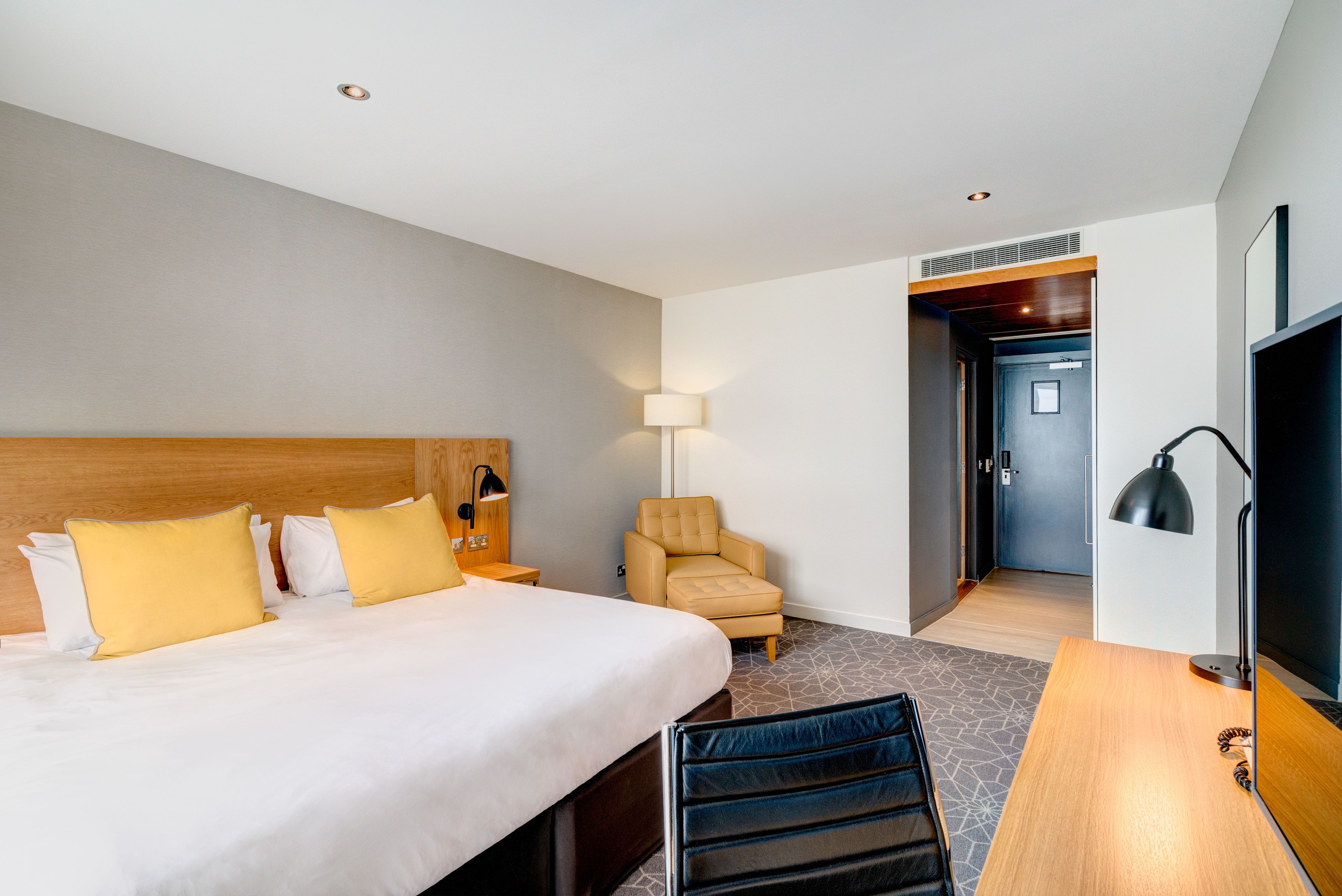 Une chambre d’hôtel avec un grand lit, un bureau, une chaise et un téléviseur.