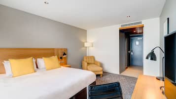 A hotel room with a large bed, a desk, a chair, and a TV.