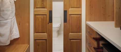 Un baño con muebles de madera, un inodoro blanco y un perchero para toallas.
