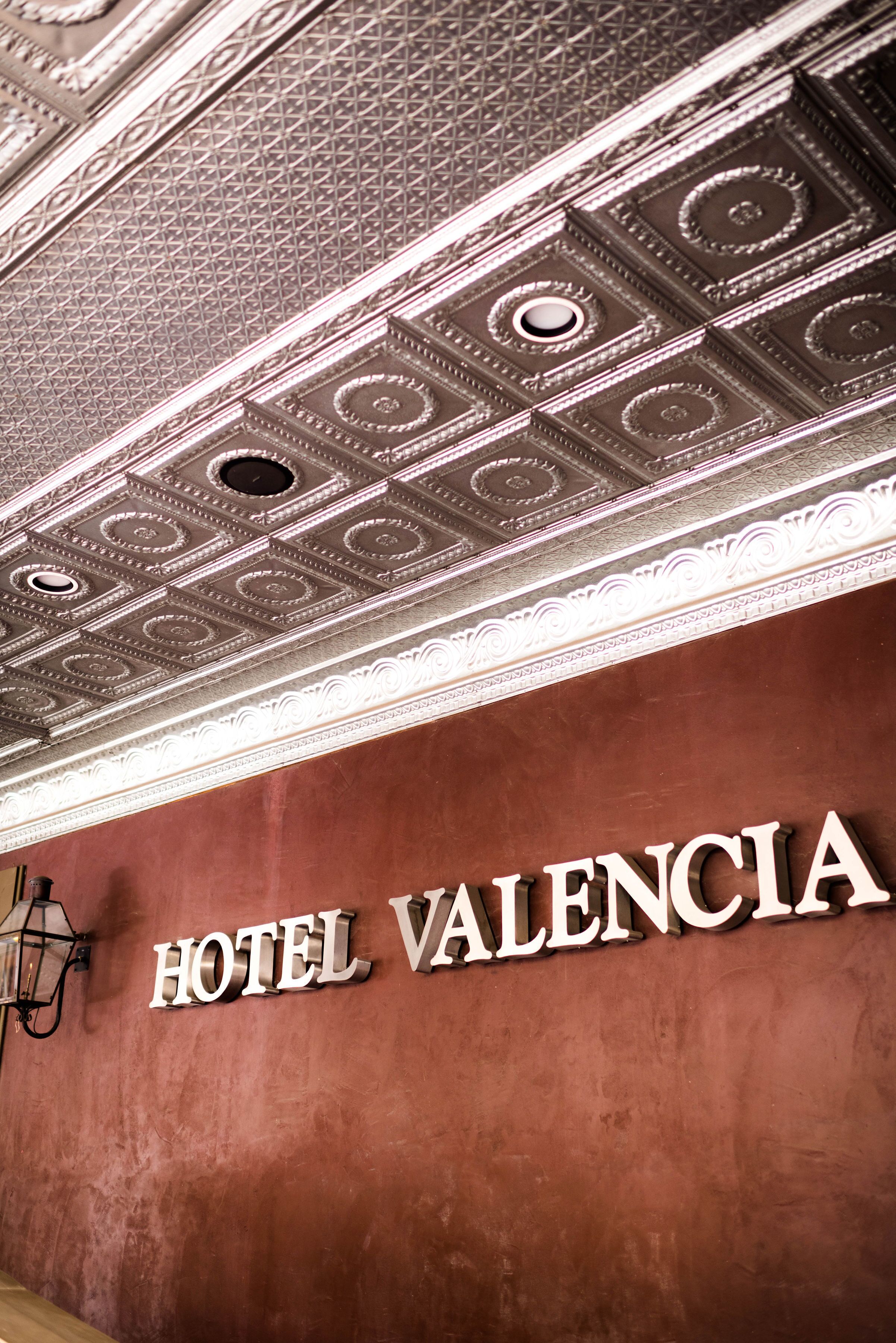 A hotel sign with the name "HOTEL VALENCIA" on a textured wall.