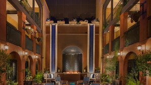 A spacious courtyard with a central fire feature, surrounded by lounge chairs and potted plants.