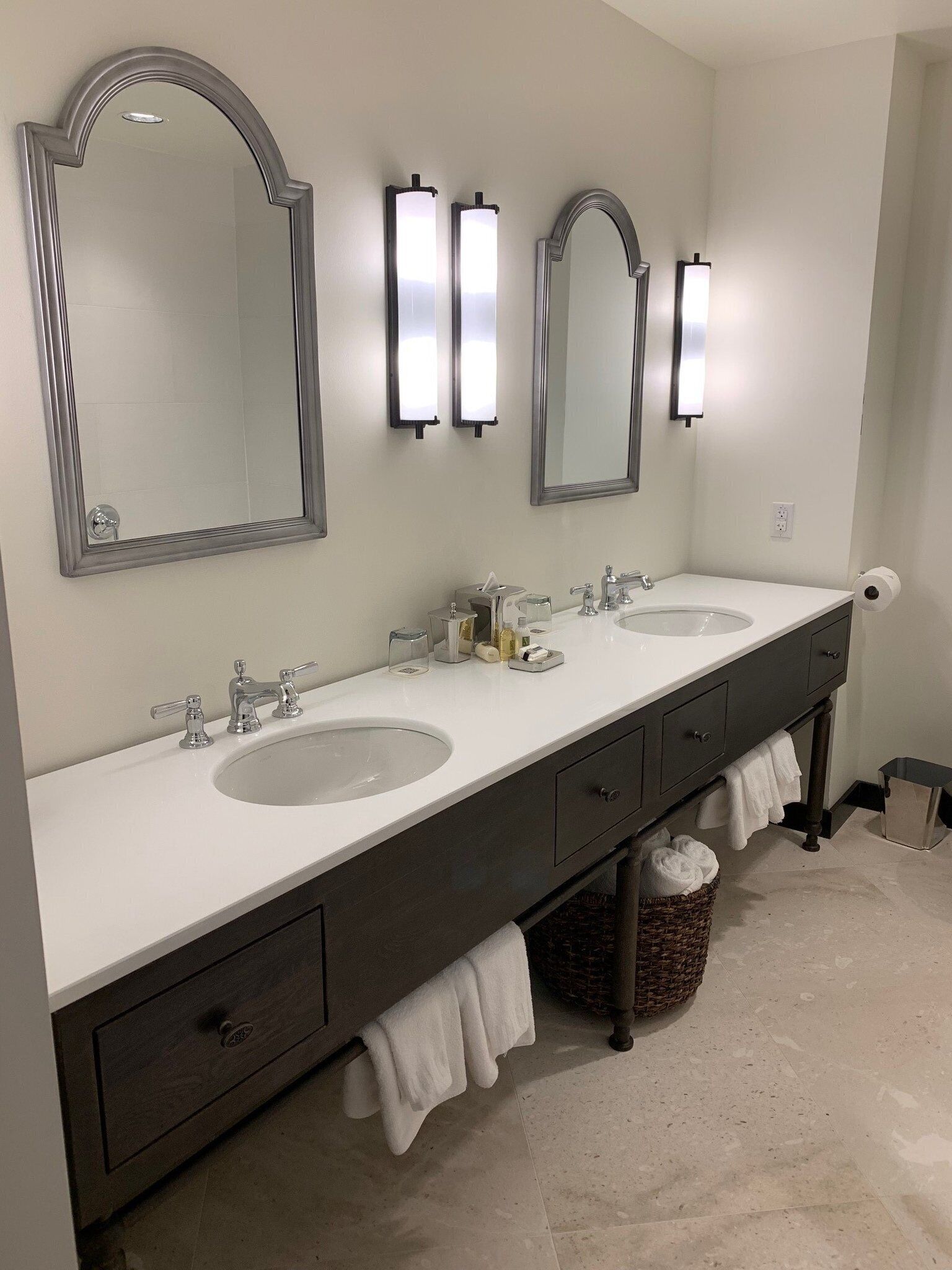 A bathroom with two sinks, a mirror, and wall-mounted lights.