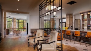 A spacious bar area with a high ceiling, wooden flooring, and a mix of bar stools and chairs.